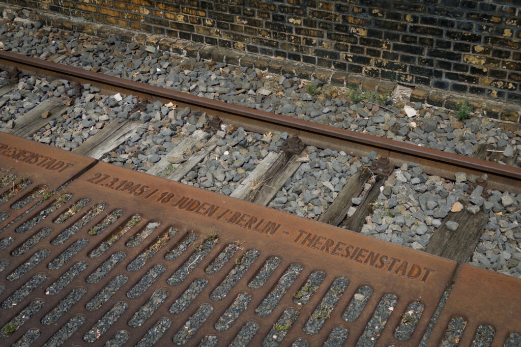 Rust stains the steel beside the railway tracks at Platform 17 in Berlin. Dates and destinations mark the deportation of Jews during the Second World War. From this platform, thousands were sent to ghettos and camps. The trains left. Few returned. The silence remains.
